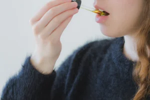 Fotografia de una mujer con un dosificador en la mano derecha con un liquido que consume de manera sublingual. La imagen se utiliza para complementar un blog sobre la tolerancia al cbd